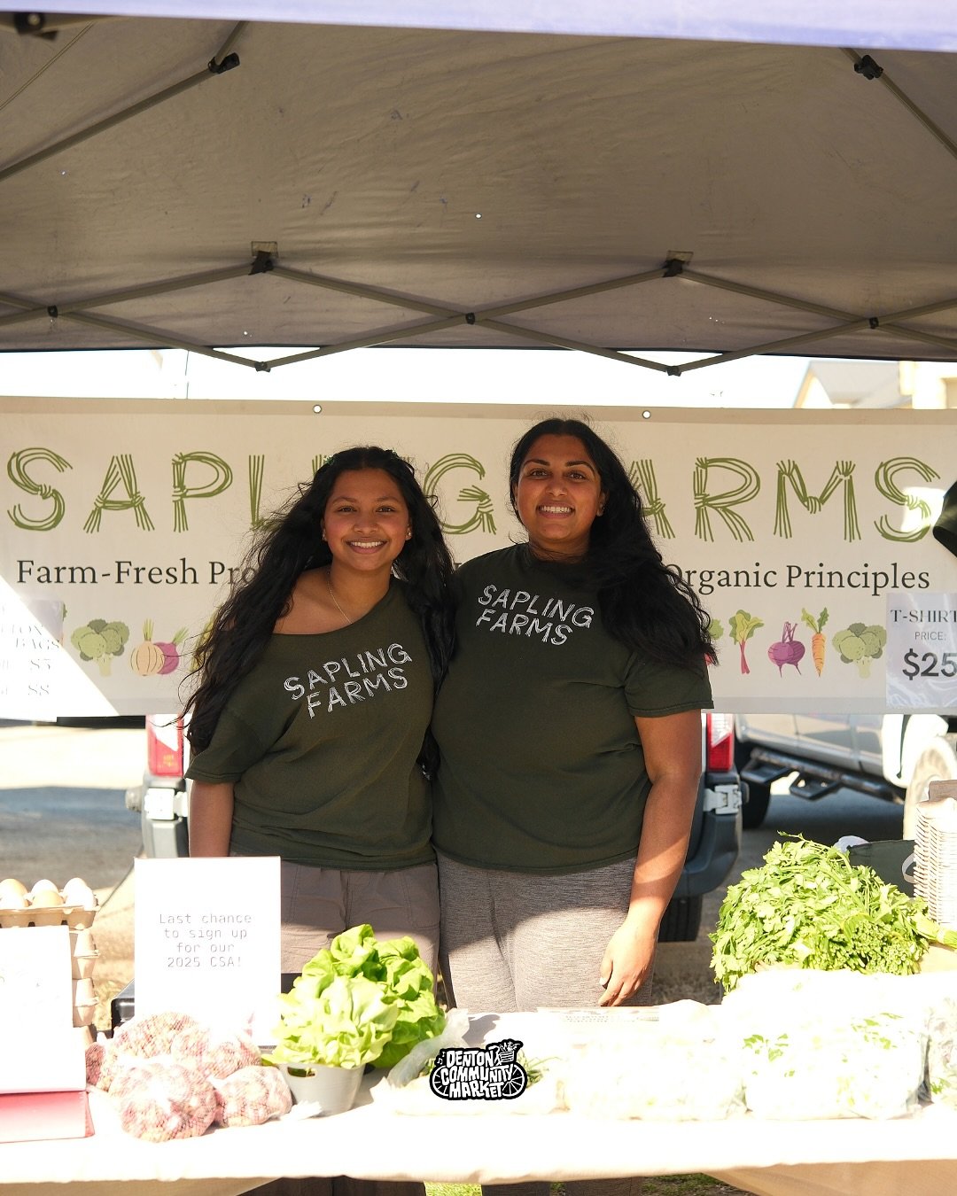 Farmers smile behind their produce stand at Denton Community Market